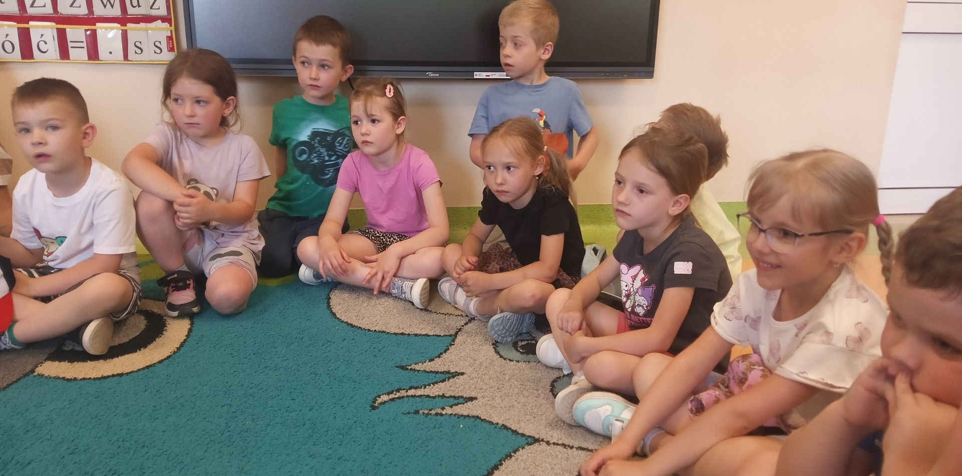 Dzieci siedzą na dywanie